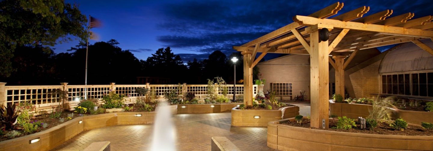 Garden patio at night with fountain and wooden canopy