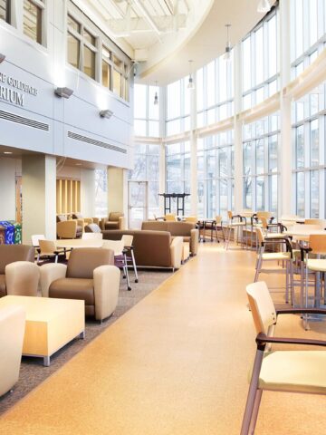 A modern campus interior with a curved glass wall on the right and an atrium entrance on the left.